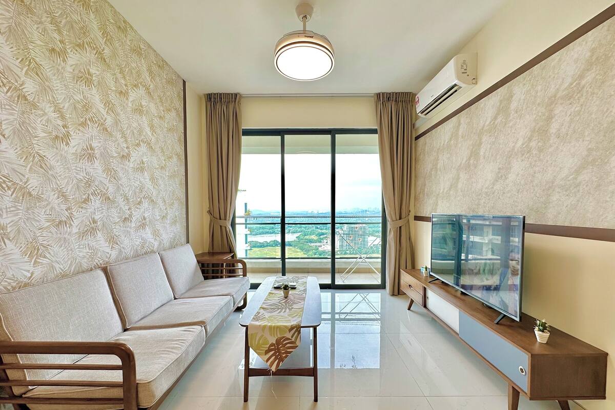 Un salon avec un canapé, une table basse, un téléviseur et un balcon offrant une vue agréable.