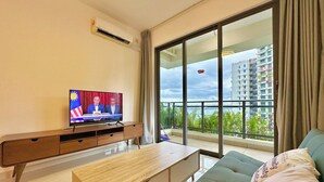 Una sala de estar moderna con un televisor mostrando un noticiero, un sofá, una mesa de centro de madera y un balcón con vistas a un paisaje urbano.