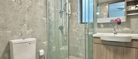 A modern bathroom with a glass-enclosed shower, a white toilet, a sink, and a mirror above the sink.