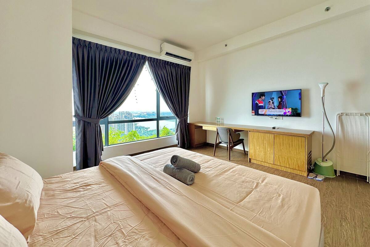 Une chambre d’hôtel équipée d’un lit, d’un bureau, d’une télévision et offrant une vue sur le paysage urbain.
