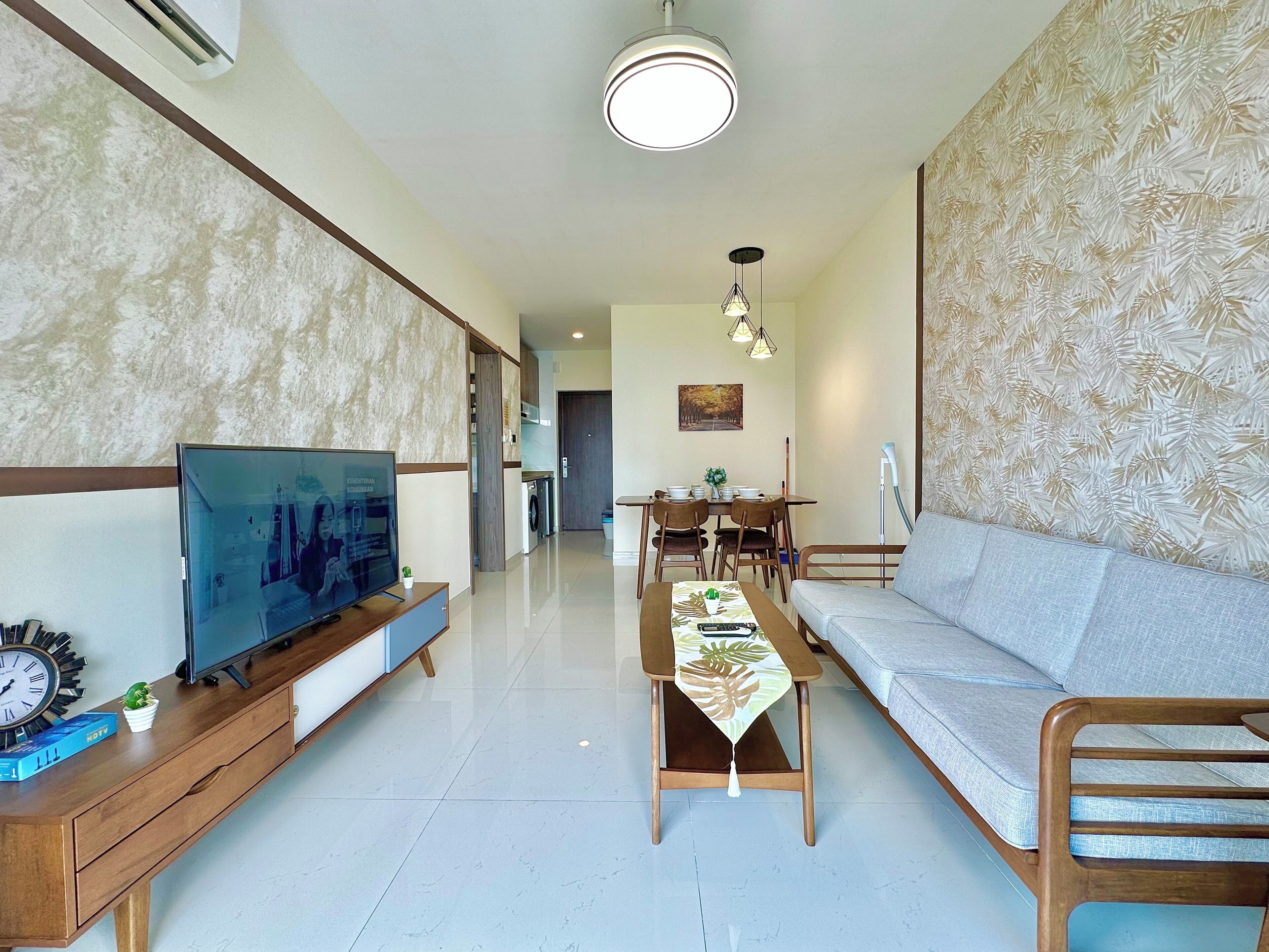 Una sala de estar moderna con televisor, sofá, mesa de comedor y un pasillo que lleva a una cocina.