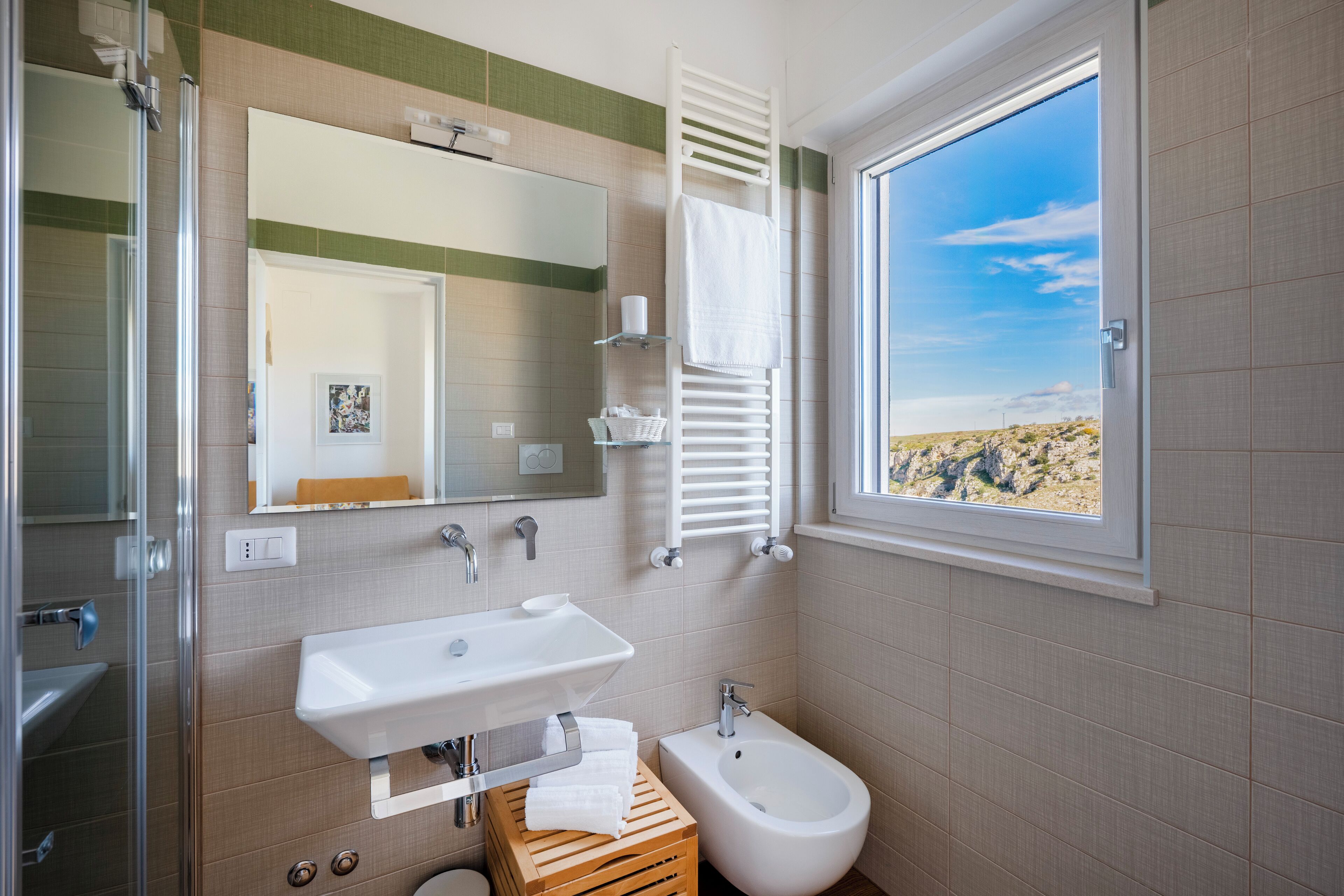 A bathroom with a sink, bidet, and a window with a desert view.