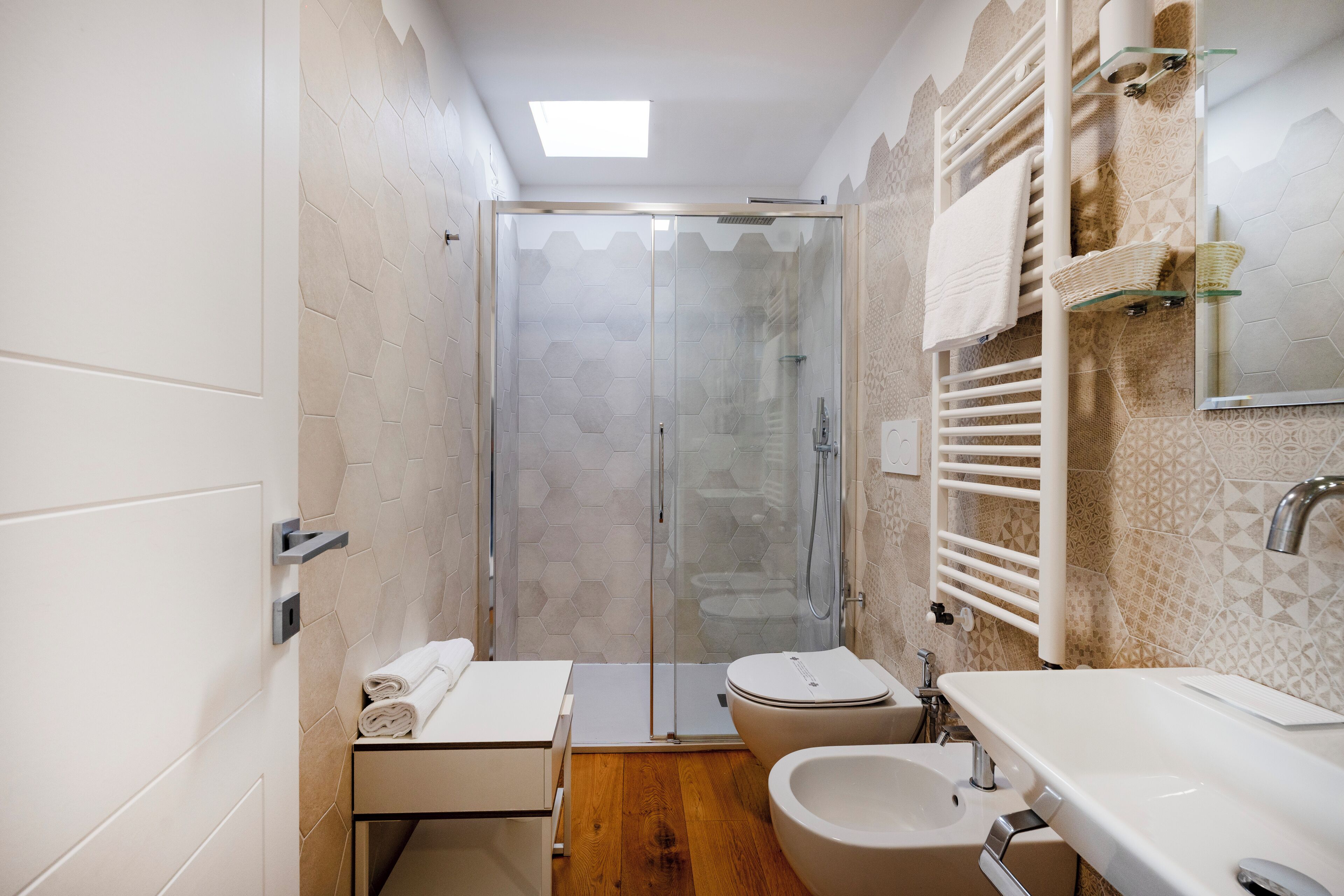 A modern bathroom with a glass shower enclosure, a toilet, a bidet, and a sink.