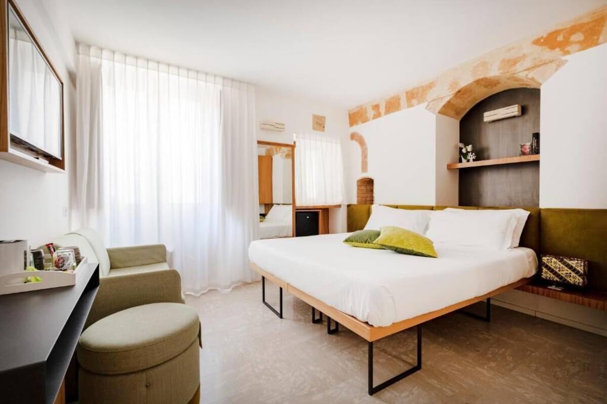 Una habitación de hotel con cama, escritorio, silla y tocador con espejo.