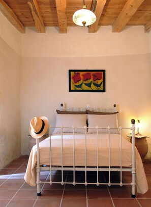 A bedroom with a bed, a hat, a lamp, and a painting on the wall. - Private traditional villa with swimming pool (Chania)