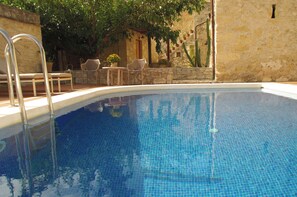 A swimming pool with a clear blue water surface, surrounded by stone walls and potted plants. - Private traditional villa with swimming pool (Chania)