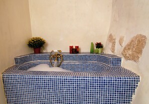 Ein Badezimmer mit einer blauen Wannenauskleidung, einem goldenen Wasserhahn und zwei Kerzen.