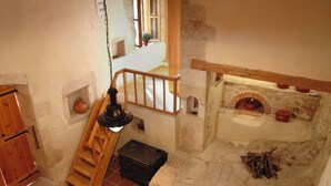 Ein rustikales Interieur mit Kamin aus Stein, einer Holztreppe und einer kleinen Holzkiste.