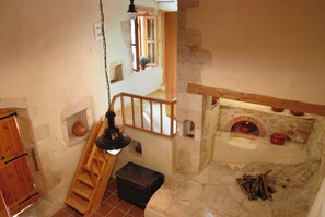 Ein rustikales Interieur mit Kamin aus Stein, einer Holztreppe und einer kleinen Holzkiste.