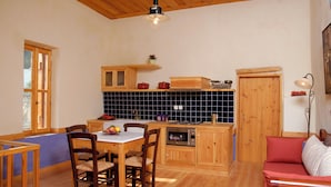 Eine Küche mit Holzausstattung, einem Esstisch mit Stühlen, einer Mikrowelle und einem roten Sofa.