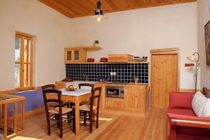 Eine Küche mit Holzausstattung, einem Esstisch mit Stühlen, einer Mikrowelle und einem roten Sofa.