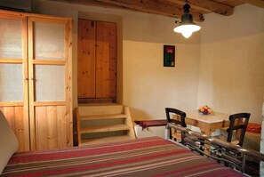 Ein Schlafzimmer mit einem Bett, einem Holzschrank, einem Esstisch mit Stühlen und einer Treppe.