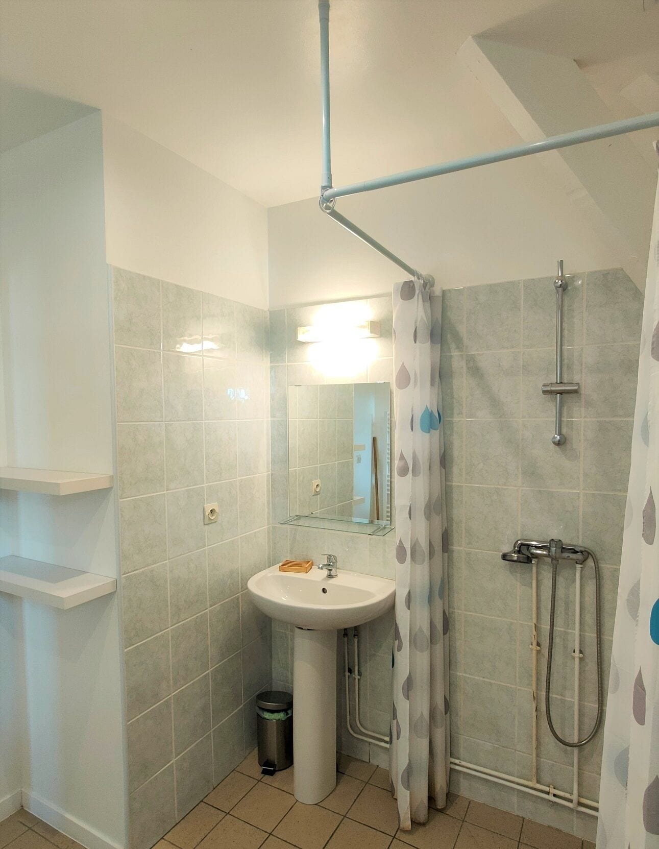 Une salle de bain avec une douche, un lavabo et un miroir.