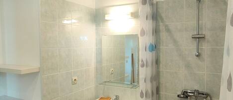 Une salle de bain avec une douche, un lavabo et un miroir.