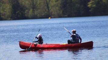 Un canoë rouge sur une eau calme, avec deux personnes qui pagayent.