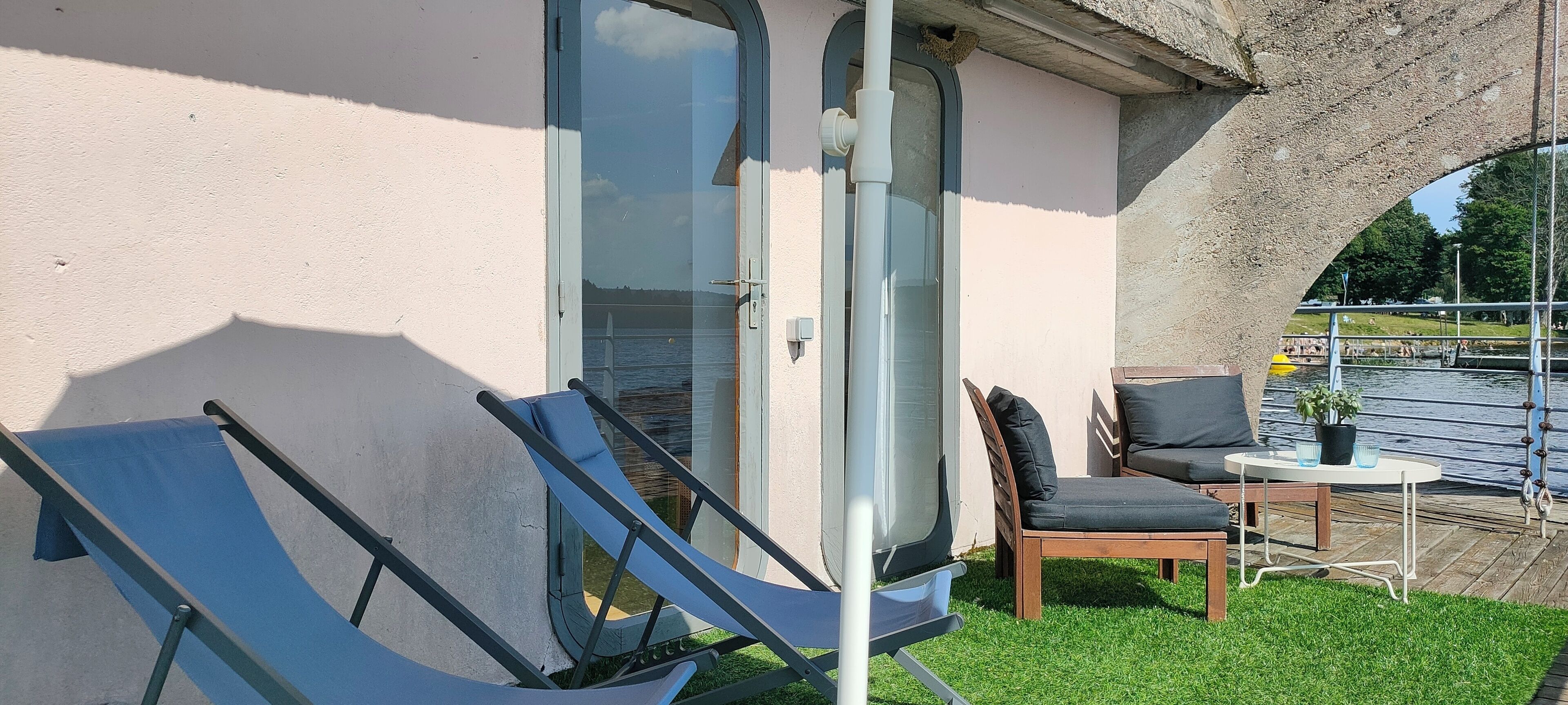 Una habitación con puerta de vidrio, una pequeña mesa con sillas y vista a un cuerpo de agua.