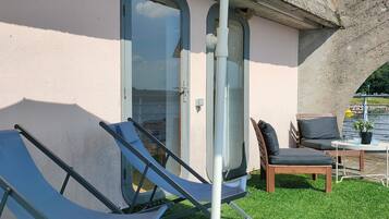 Una habitación con puerta de vidrio, una pequeña mesa con sillas y vista a un cuerpo de agua.