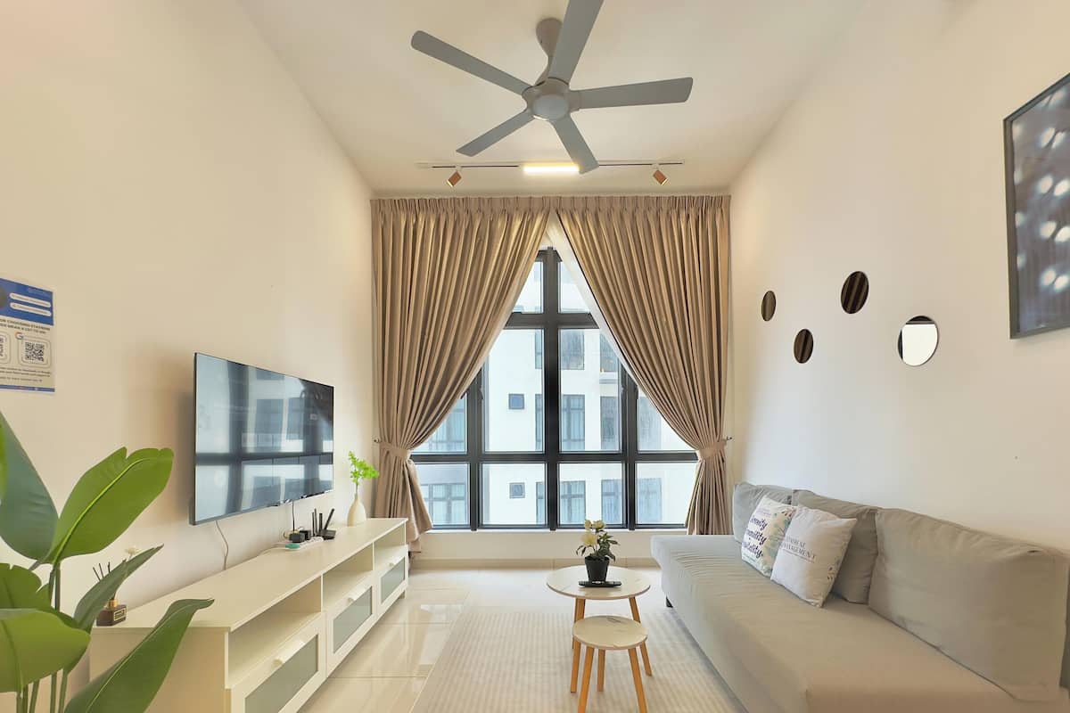 A modern living room with a ceiling fan, a flat-screen TV, a sofa, a coffee table, and a large window with curtains.