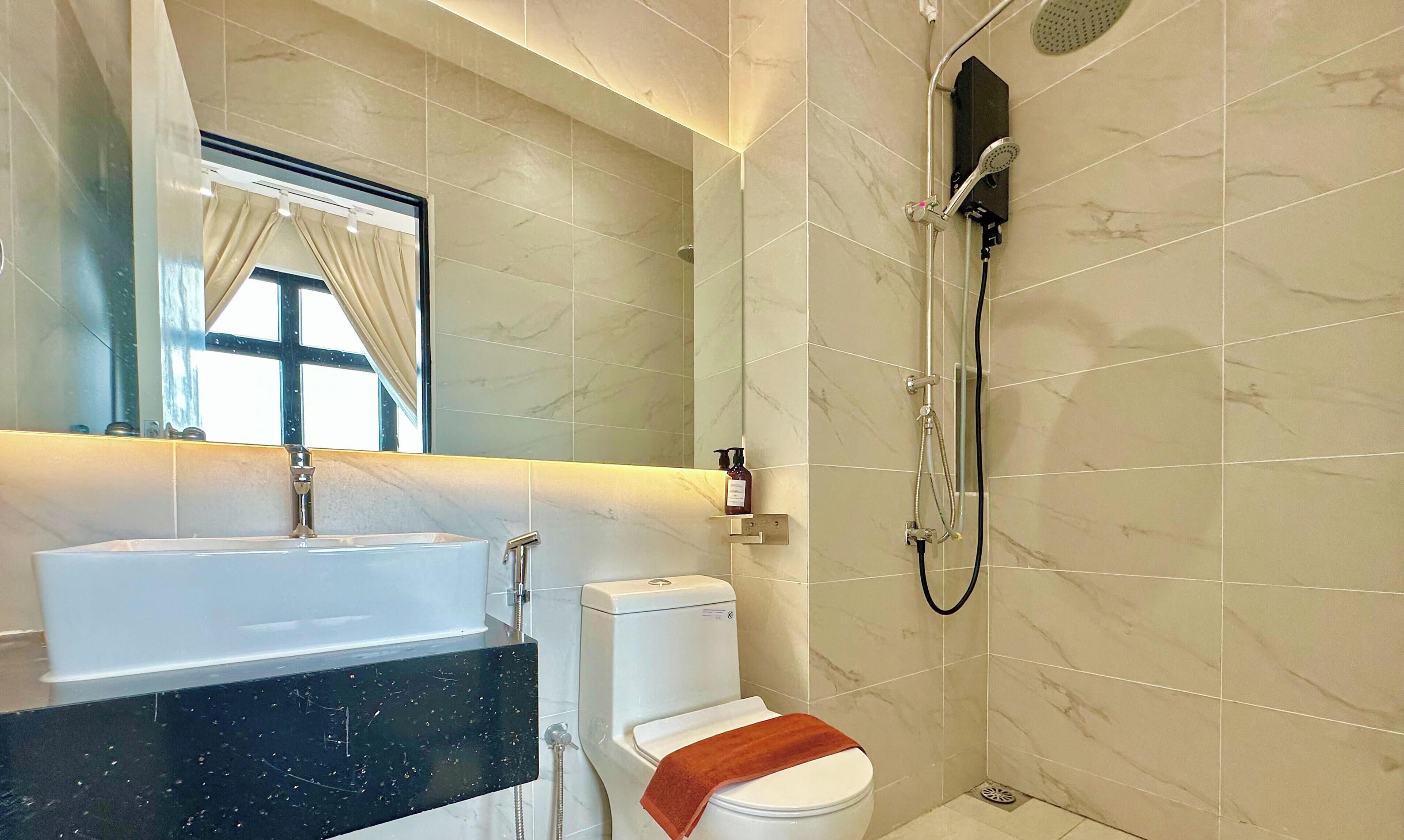 A bathroom with a sink, toilet, shower, and a mirror.