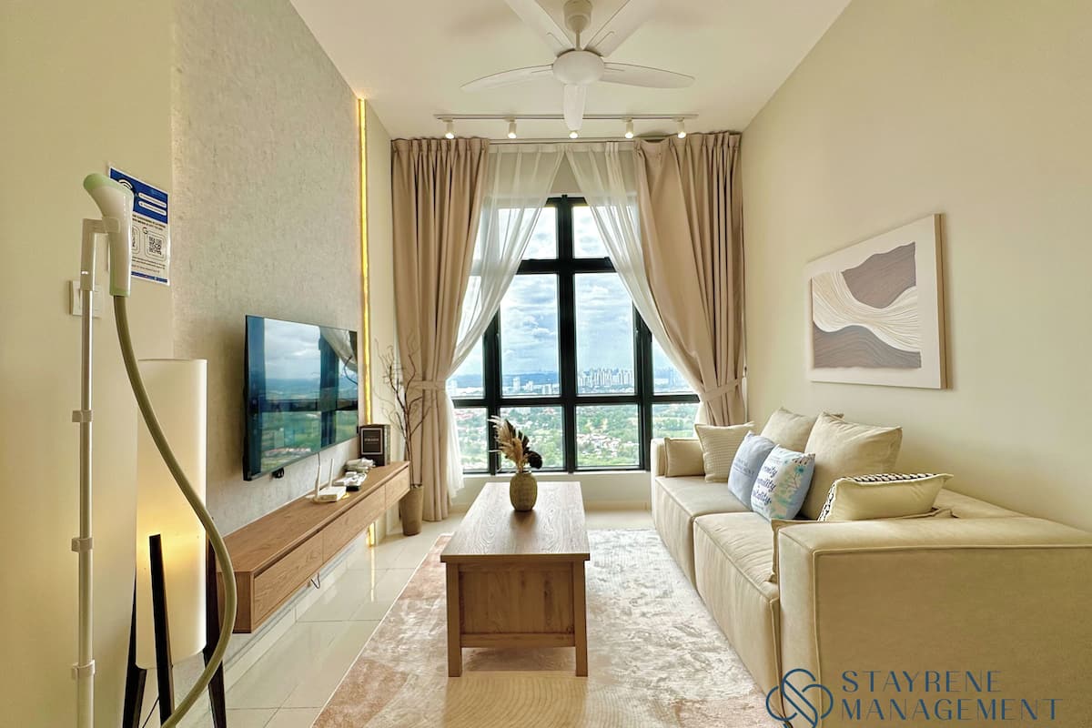 A modern living room with a flat-screen TV, a wooden coffee table, a beige sofa, and a large window offering a city view.