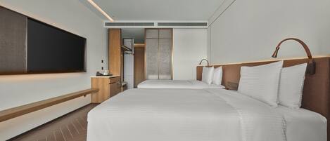 Una habitación de hotel moderna con una cama grande, un televisor montado en la pared y un vestidor.