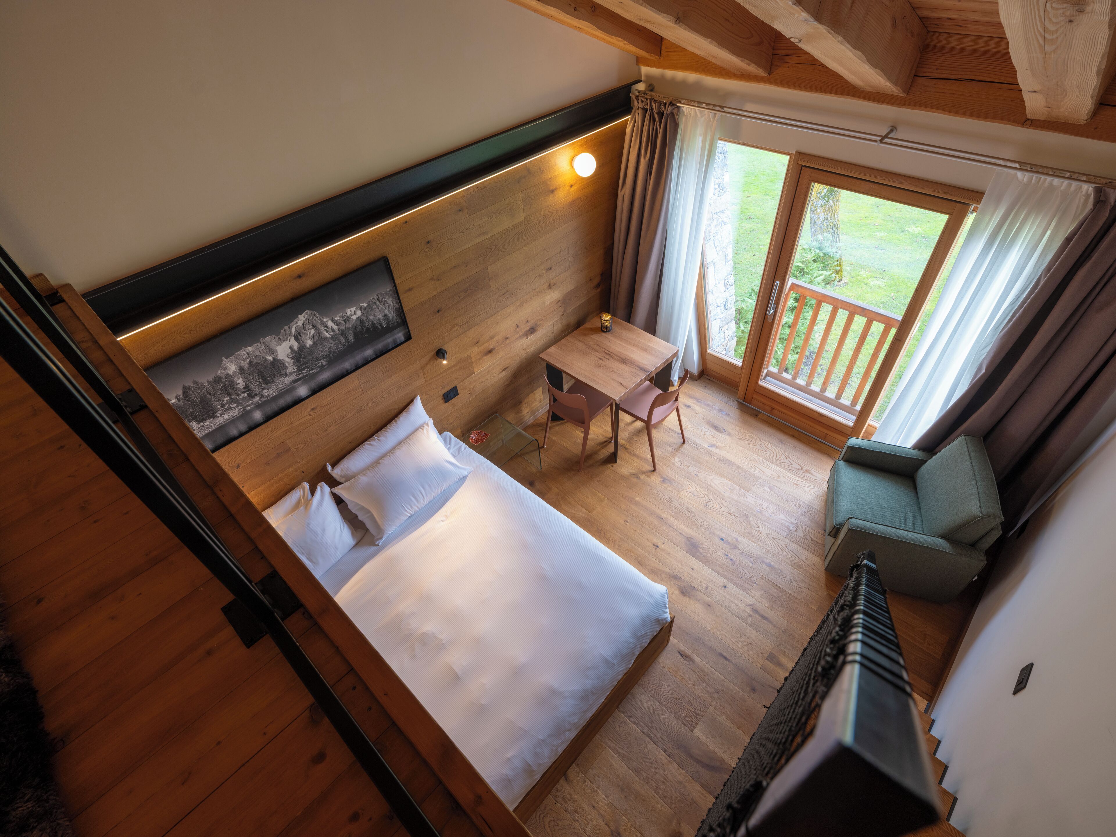 Un dormitorio con cama, una mesa y una silla. Cuenta con un balcón y vistas al exterior.