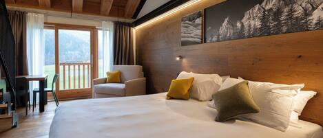 A bedroom with a large bed, a wooden headboard, a chair, and a view of the outdoors.