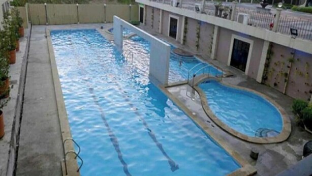 A rectangular swimming pool with a diving board and a smaller circular pool. - Cozy 1-bedroom condo with AC in charming Muntinlupa (Muntinlupa)