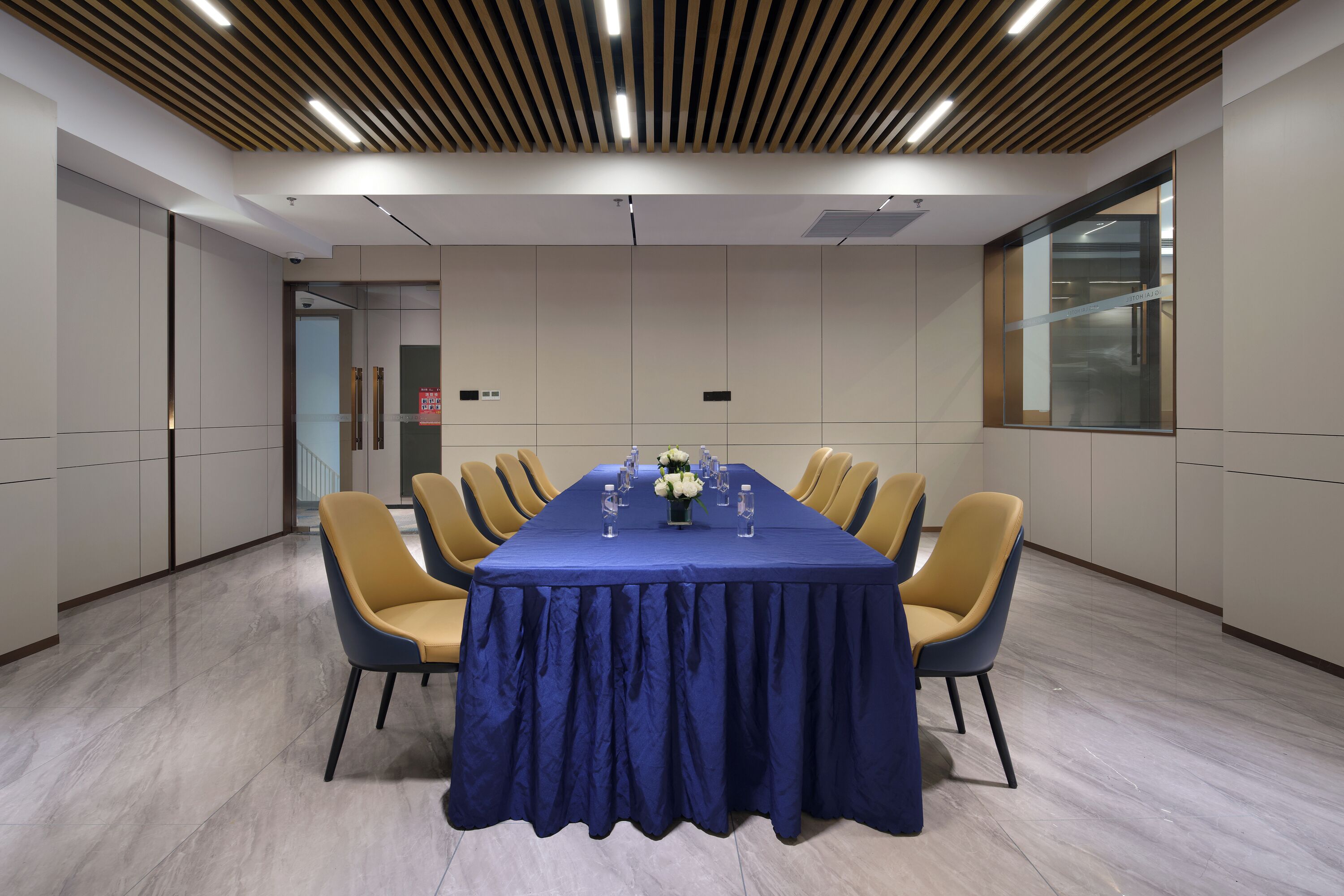A conference room with a long table, yellow chairs, and a blue tablecloth.