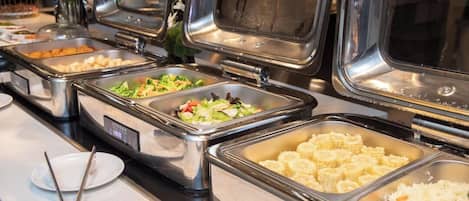 A buffet with various food options including salads, rice, and corn.