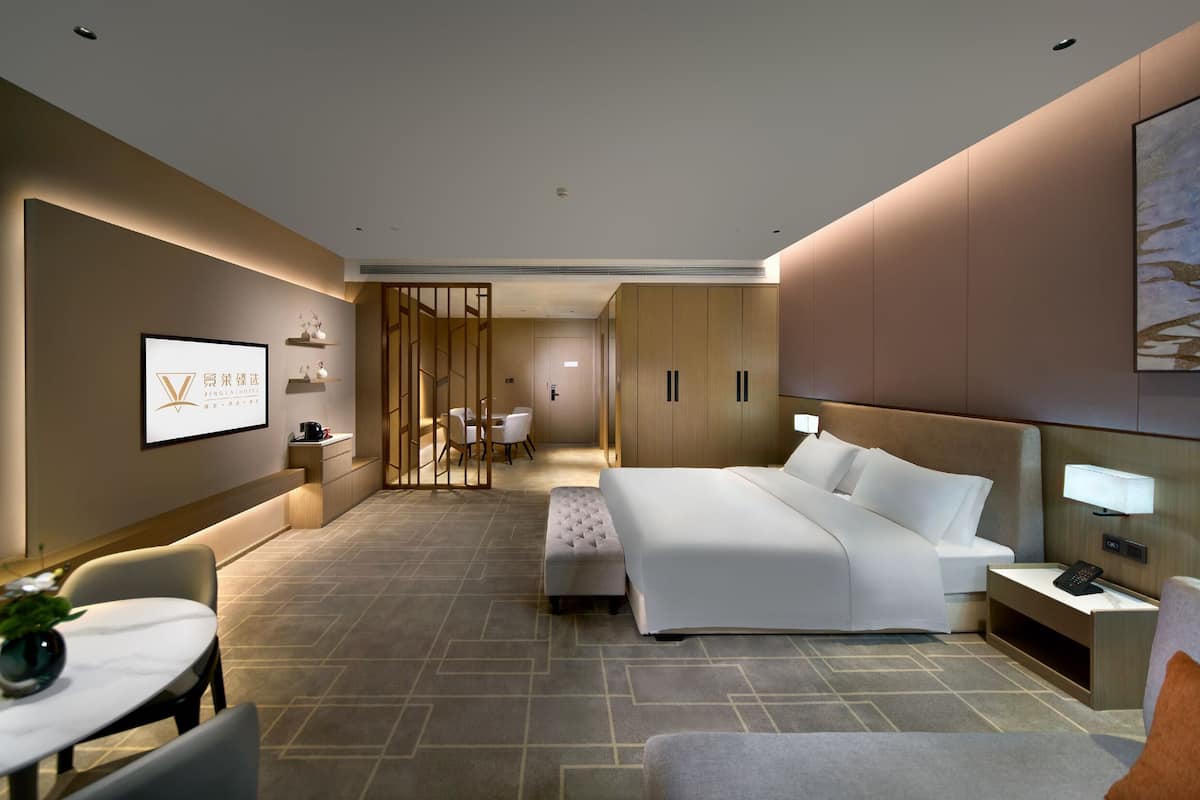 Habitación de hotel moderna con una cama grande, un escritorio, una silla y una pequeña mesa con una planta.
