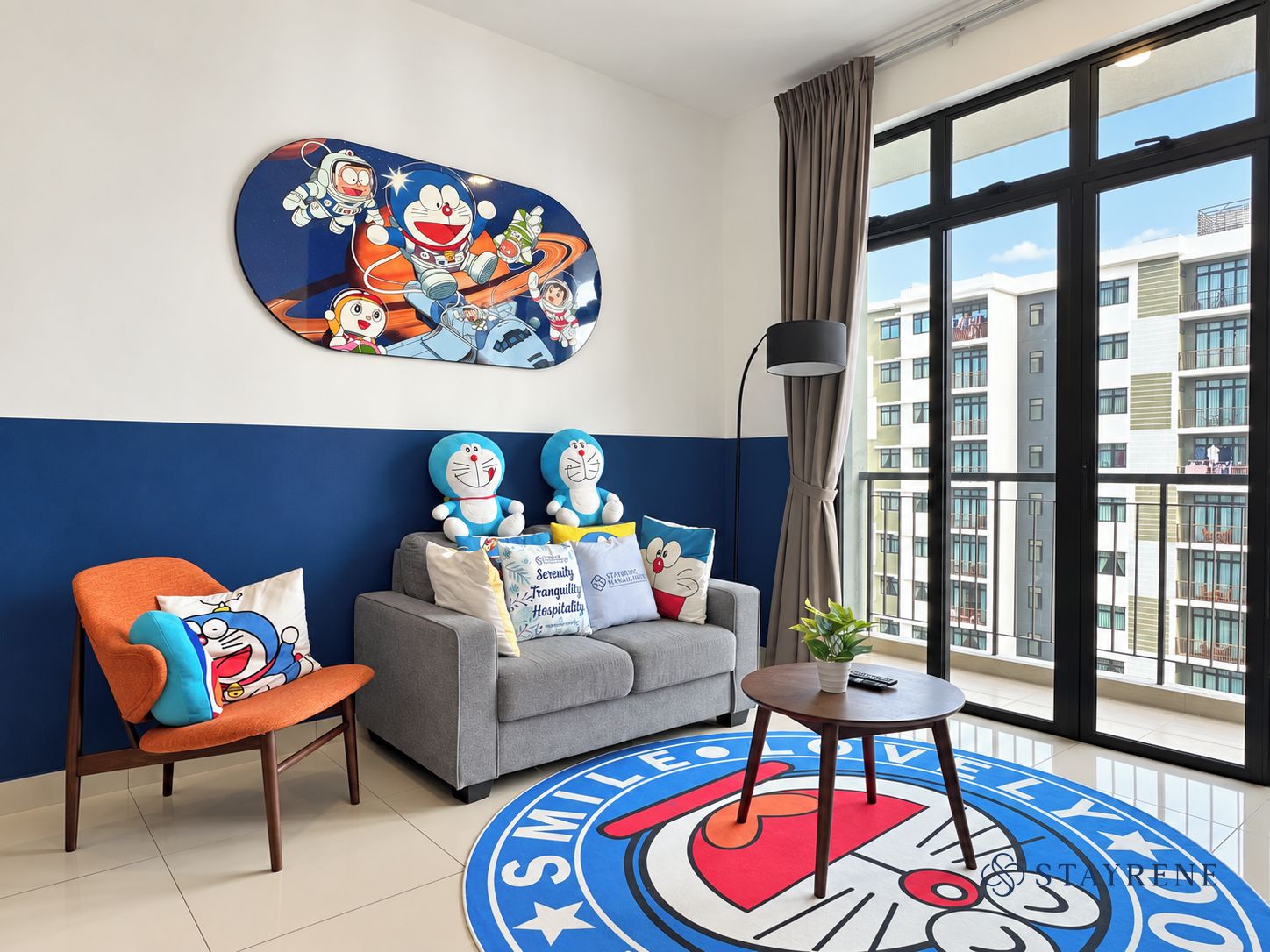 Une chambre d’hôtel avec un canapé, un fauteuil et une grande fenêtre donnant sur des immeubles.