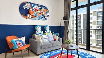 Une chambre d’hôtel avec un canapé, un fauteuil et une grande fenêtre donnant sur des immeubles.