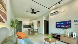 Een moderne woonkamer met een bank, een eethoek, een televisie en een airconditioner.