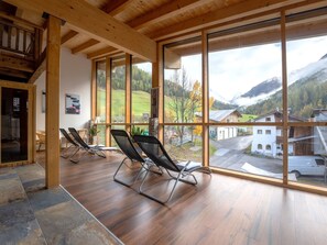 Ein geräumiges Zimmer mit großen Fenstern und Blick auf eine gebirgige Landschaft.