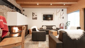 Una sala de estar moderna con chimenea, sofás de cuero, una mesa de centro de madera y un televisor montado en la pared.