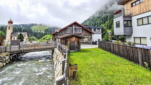 Vista a la orilla del río con un puente de madera, una iglesia y edificios modernos.