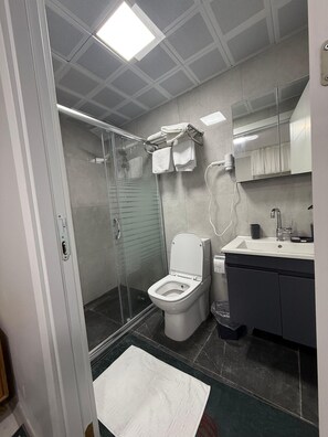 Habitación económica | Baño | Ducha, cabezal de ducha tipo lluvia, secador de pelo y zapatillas