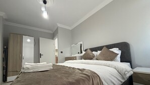 Quarto com cama, mesas de cabeceira, guarda-roupa e espelho.