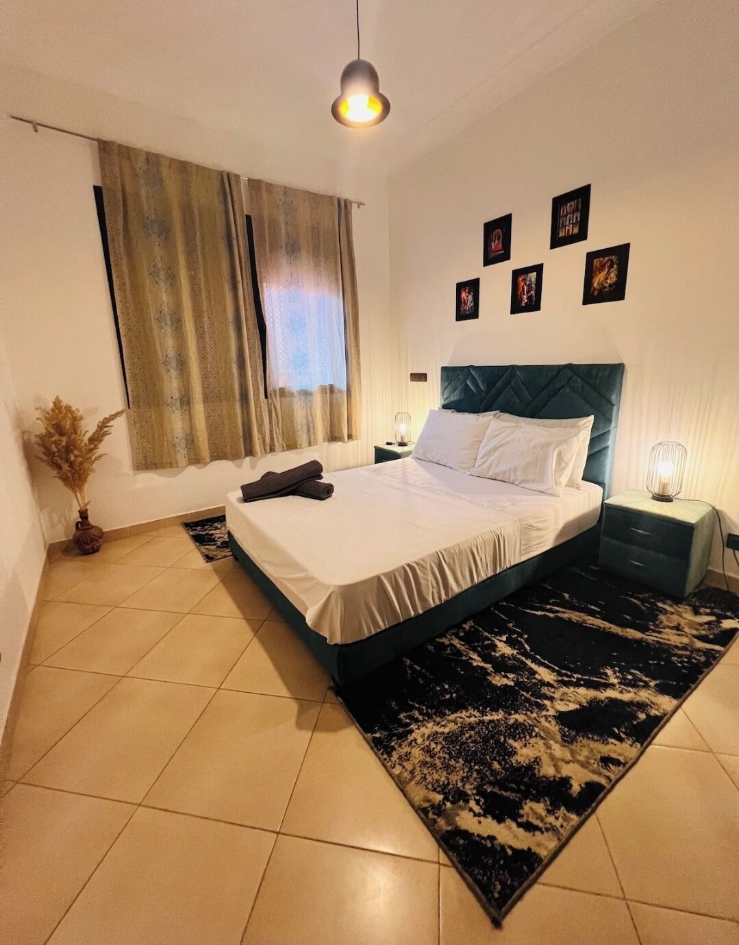 A neatly arranged bedroom with a bed, a nightstand, a lamp, and a window with curtains.