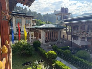 A traditional building with a courtyard, flags, and a dog. - Kaila Guest House (Bumthang)