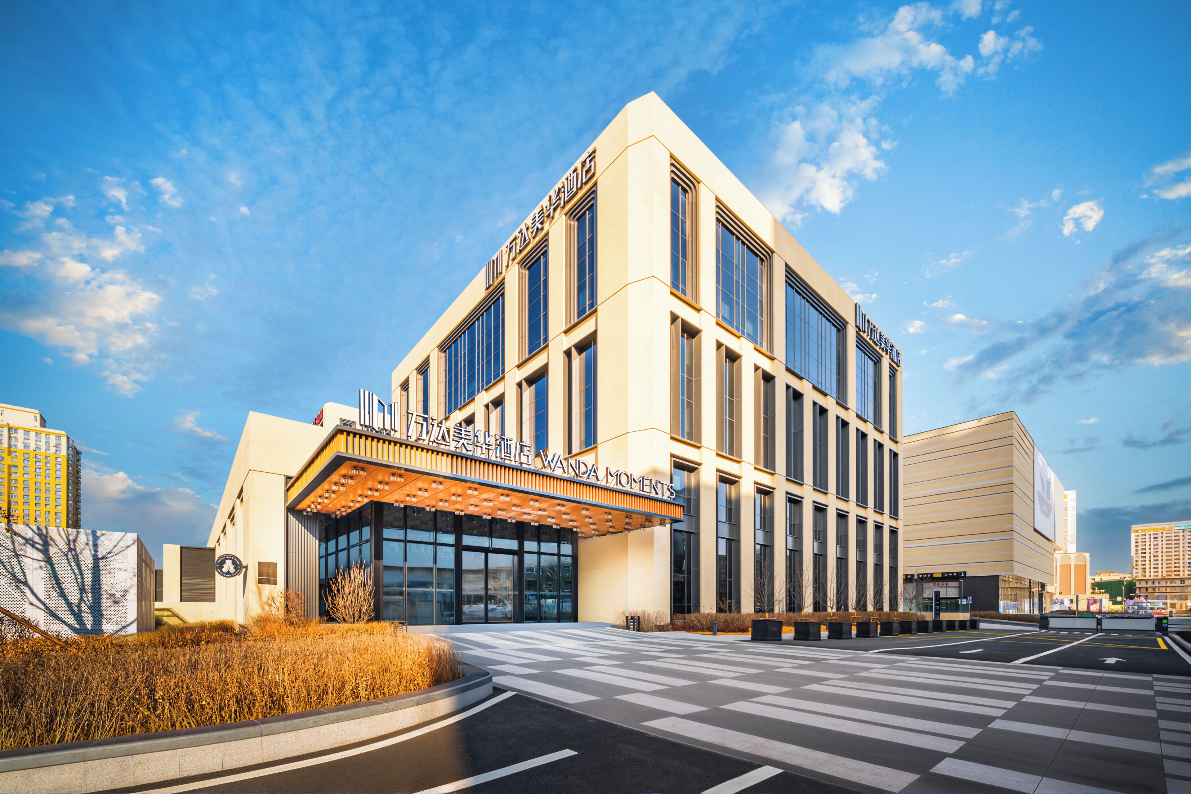 A modern hotel with a prominent entrance, large windows, and a clear sky.
