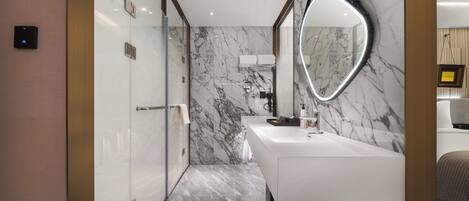A modern bathroom with a marble wall, a large mirror, and a white sink.