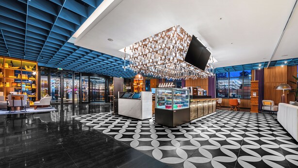 A modern lobby with a geometric patterned floor, a central seating area, and a unique hanging light fixture. - Wanda Moments Changchun (Changchun)