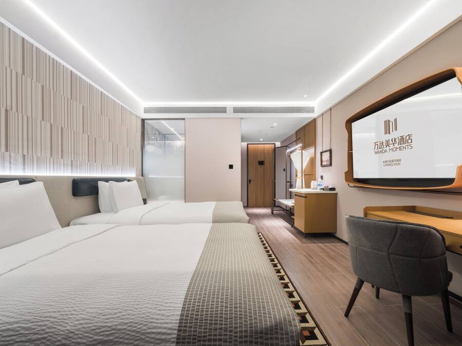 A modern hotel room with a large bed, a desk, and a large mirror.