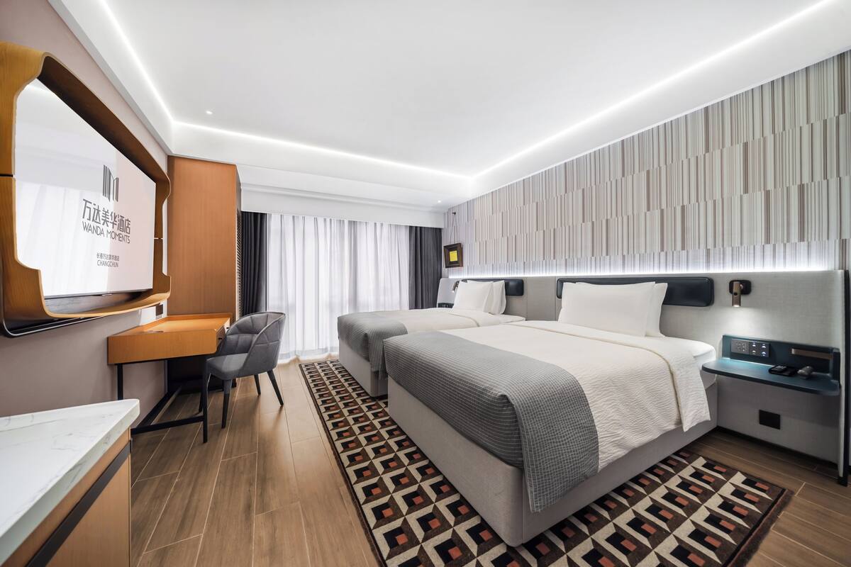 A modern hotel room with a large bed, a desk, and a TV.