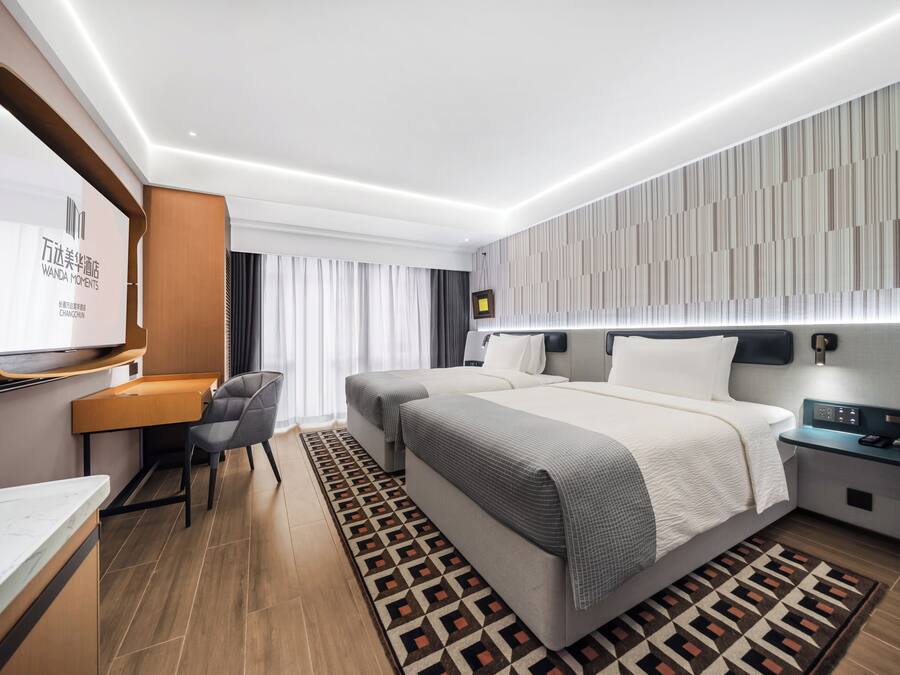 A modern hotel room with a large bed, a desk, and a TV.
