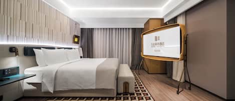 Una habitación de hotel moderna con cama, mesita de noche, televisor y alfombra estampada.