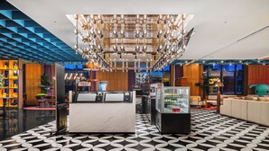 A modern lobby with a check-in counter, seating area, and a patterned floor. - Wanda Moments Changchun (Changchun)