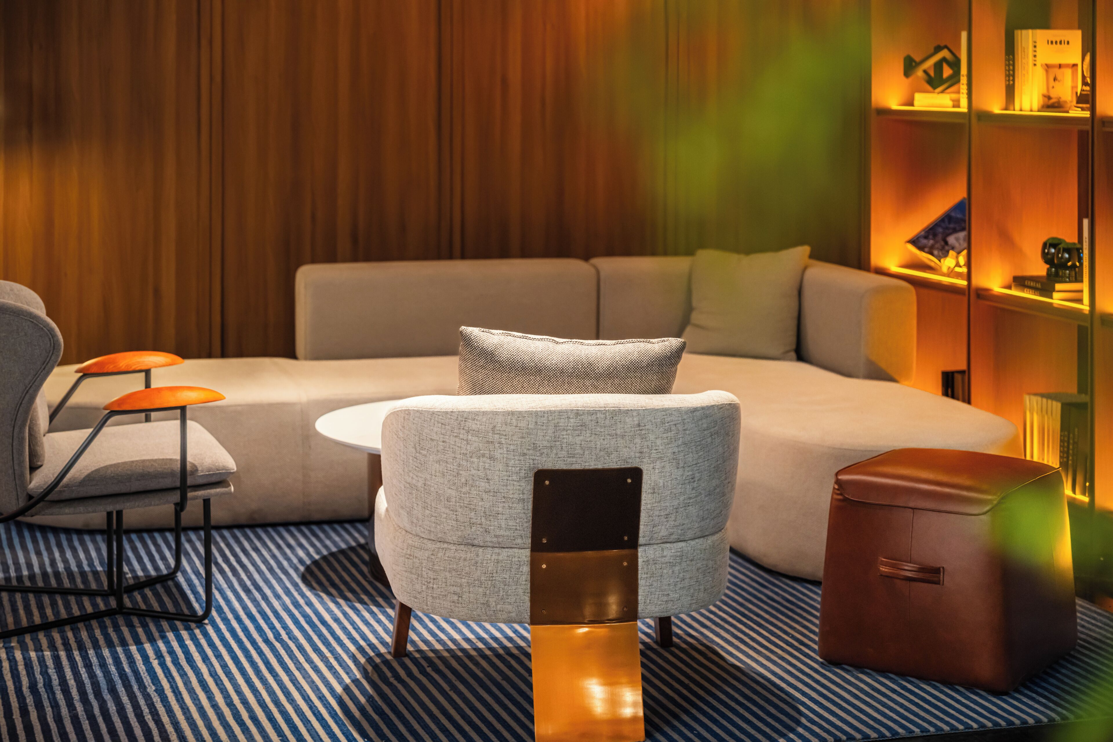 A modern living room with a sofa, a small round table, and a bookshelf.